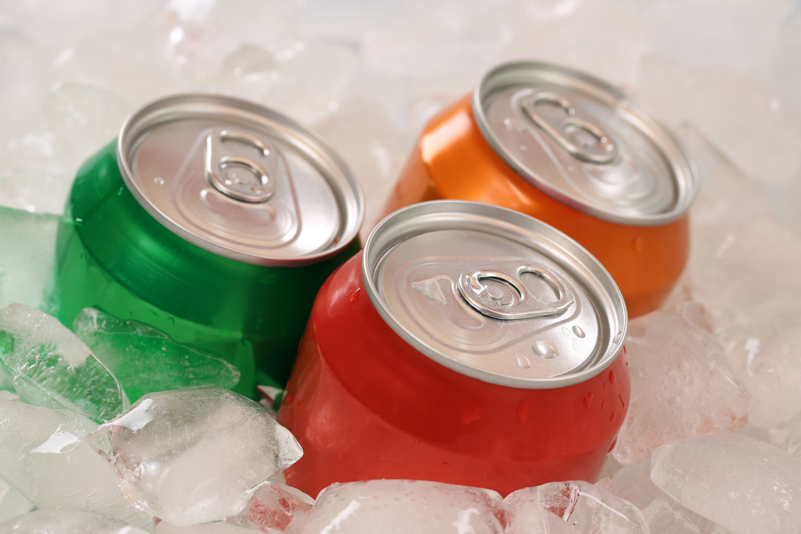 Cold cola and lemonade in cans on ice cubes